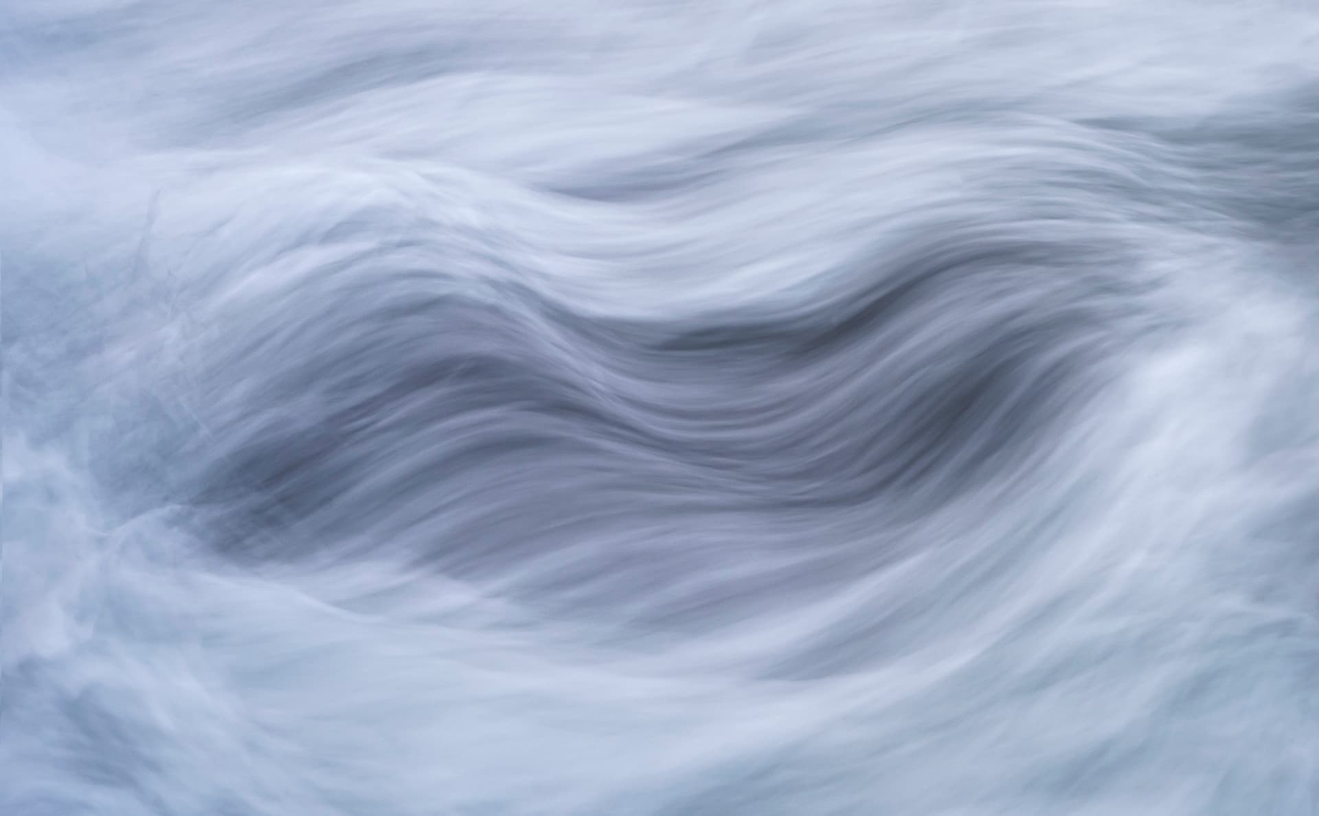 Abstract close-up of fast-flowing water with soft blue and white streaks
